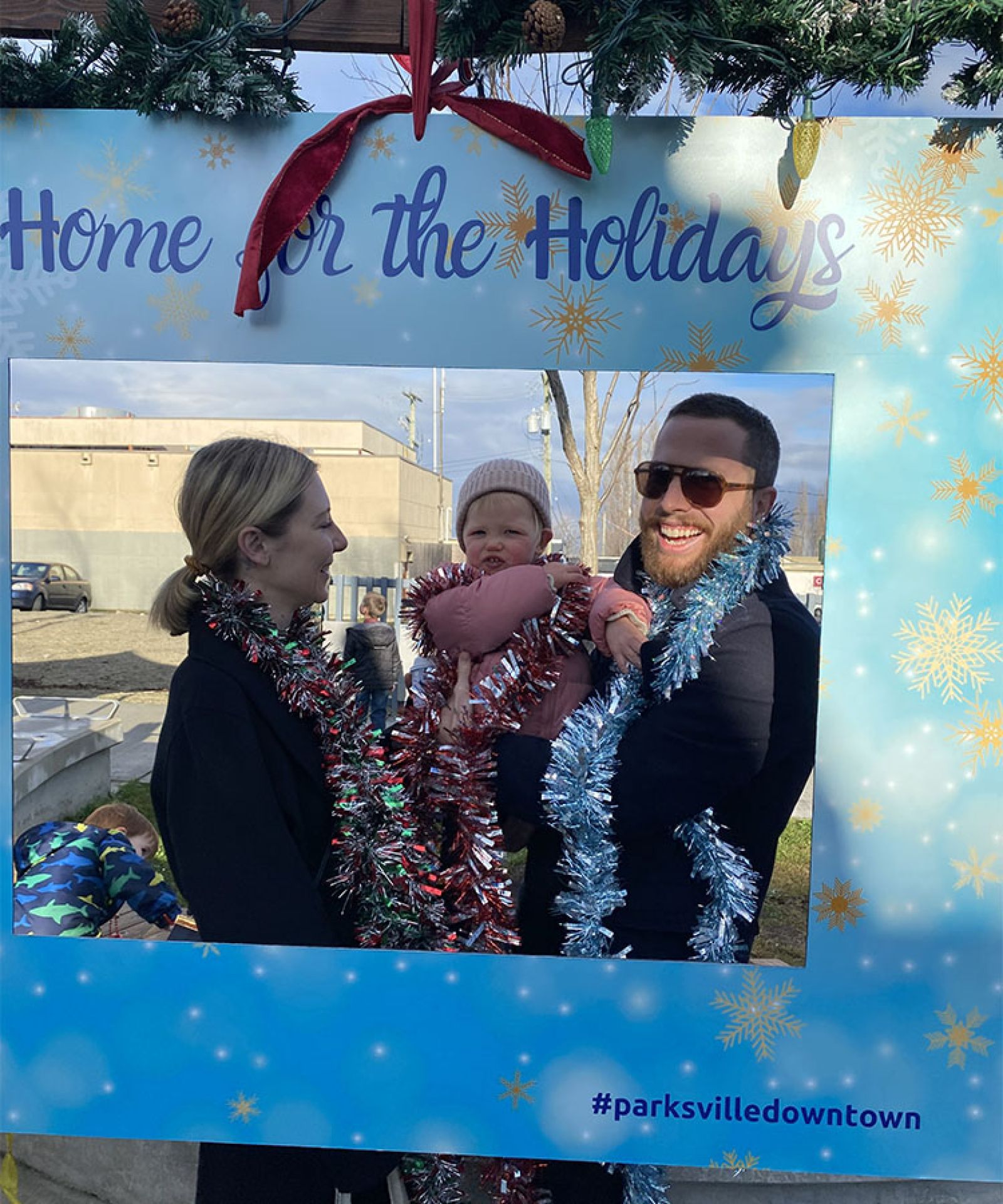 Residents posing inside Home for the Holidays frame in downtown Parksville Volunteer for Parksville Downtown